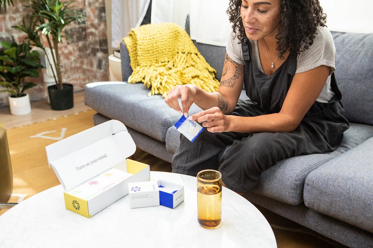 Frau zu Hause prüft eine Medikamentenpackung — Preise in 100+ Apotheken vergleichen
